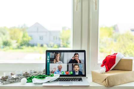 A happy family with a child is celebrating Christmas with their friends on video call using webcam....