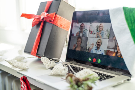 A happy family with a child is celebrating Christmas with their friends on video call using webcam....