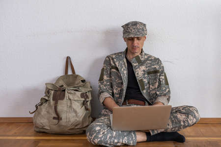 Smiling young man in navy uniform holding a laptop against white background.の写真素材
