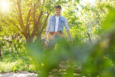 a man with a chainsaw. removes plantings in the garden from old trees, harvests firewood.の写真素材