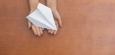 Childs Dream. Childs hand launching white paper airplane