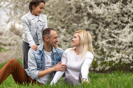 Happy male and female playing with child outside, spring.