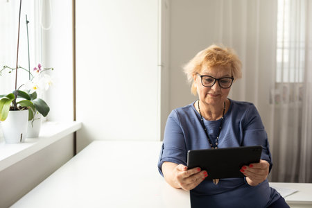 pretty senior woman using tablet computer at home