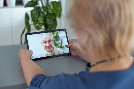Senior woman making video call from tablet computer at homeの写真素材