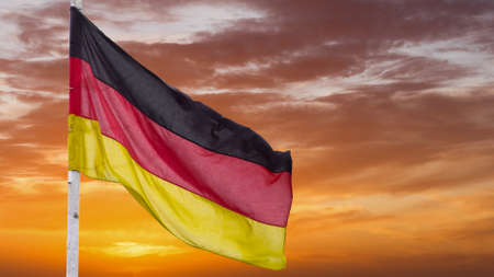 The official flag of Germany waving on a blue sky background. Horizontal banner design, with the German flag hanging on a sunny background with white clouds. Deutschland flag wide bannerの写真素材