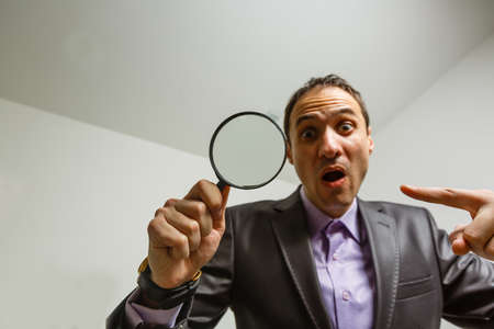 Man hand holding magnifying glass. Data search and analysis, conducting research, nuances, important details study, preparation for exams conceptの写真素材