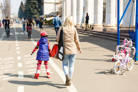 Mother and her daughter wearing roller skates in park