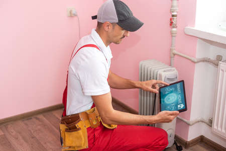 plumber at work. Installing water heating radiator with tabletの写真素材