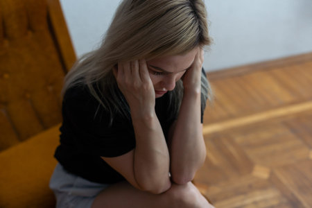 Shot of a young woman holding her head in discomfort due to pain at home.