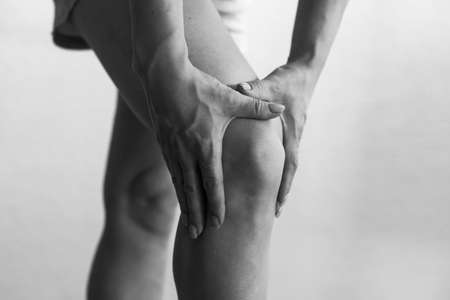 Closeup woman hand hold knee with pain symptom, health care and medical conceptの写真素材