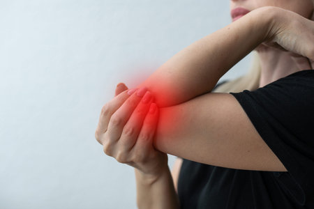 Middle age woman is holding her sore elbow. All is isolated on the white background. Empty place for your text is in the left half of the photoの写真素材