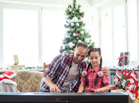 father and daughter playing the piano at christmasの写真素材