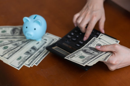 Woman holding money, piggy bank at table, closeup