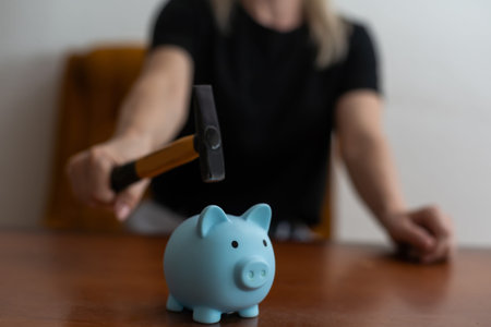 Woman holding hammer over piggy bankの写真素材