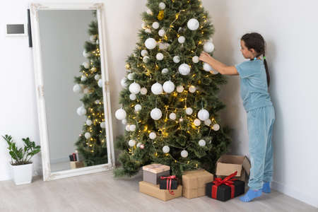 Little girl decorating christmas tree with toys and baubles. Cute kid preparing home for xmas celebrationの写真素材