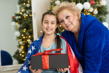 Christmas in America. grandmother and granddaughter celebrate Christmas or New Year on american flag background. Happy family in USAの写真素材