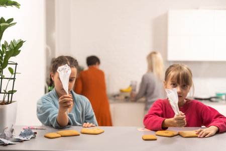 two little sisters decorating homemade cookies in the kitchen at home.