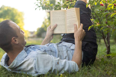 a man reads the Bible on the grass at a parkの写真素材