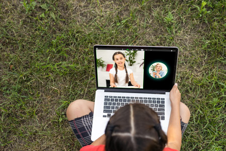 Home schooling. A girl is sitting at a table with a laptop during an online video chat of a school...