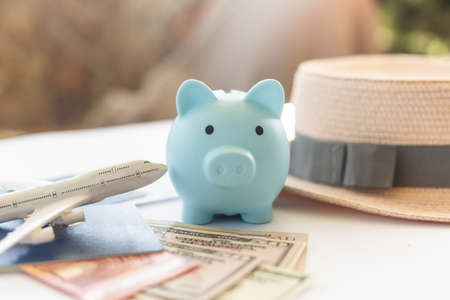 Save money for airplane tickets, planning travel budget concept. Airplane model, piggy bank on wooden tableの写真素材