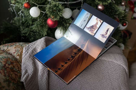 Photo book family photo album under the Christmas tree surrounded by Christmas giftsの写真素材
