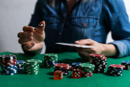 A woman plays in a casino. opening cards to raise bets. Against the background of chips. Poker victoryの写真素材