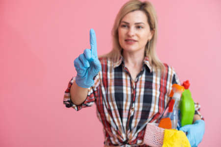Bottles with household chemicals in a wicker basket in the hands of a caucasian woman. pink background. Place for text.の写真素材