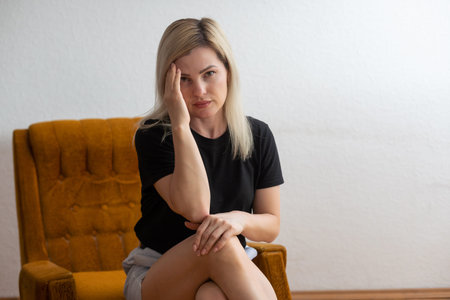 Shot of a young woman holding her head in discomfort due to pain at home.