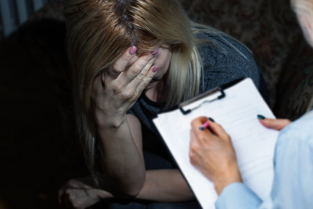 A young beautiful ukraine woman is crying while sitting with psychologistの写真素材