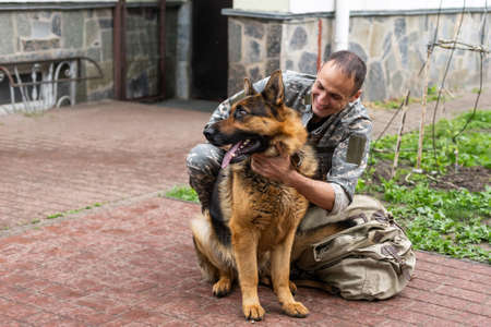 Man in military uniform with German shepherd dog, outdoors.の写真素材