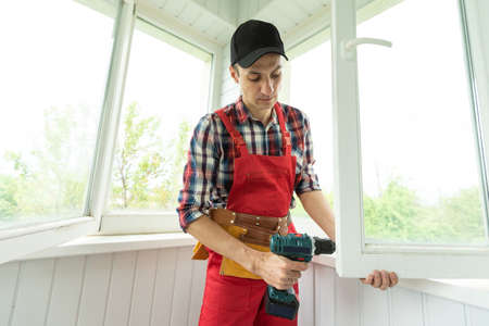 Construction worker repairing plastic window with screwdriver indoors, closeup.の写真素材