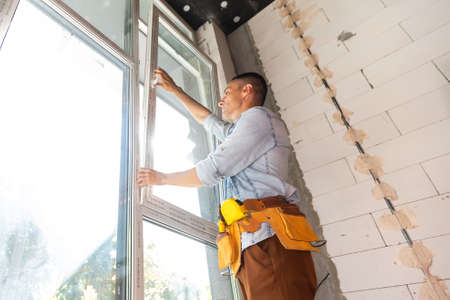 Construction worker installing window in houseの写真素材
