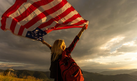Woman holding USA flag on top of mountain and enjoys the view of the autumn rocks hills. Celebrating...
