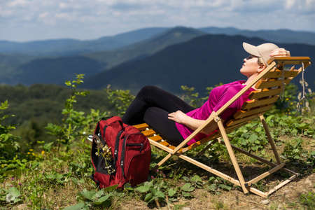stylish traveler woman relaxing in mountains. hipster on top of mountain, resting. space for text. atmospheric moment. wanderlust and travel concept.の写真素材