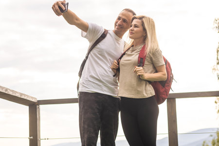 Horizontal sideview shot of a young couple in summer outfit enjoying the mountain view from terrace. Copy space.の写真素材