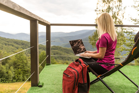 Woman freelancer with laptop working on the lounger in the mountains