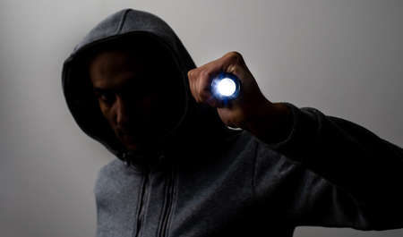 Close up portrait of a courageous man in a deep dark hood on a black background. The concept of secrecy of secrets and people hiding from the government. Hackers and thieves. Low key.の写真素材