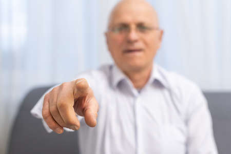 Mature man pointing with his finger at you on grey backgroundの写真素材