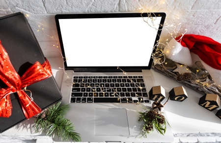 Laptop computer with white blank empty mock up screen on Merry Christmas table with presents gifts boxes in warehouse background. Ecommerce website xmas online shopping and shipping delivery, bannerの写真素材