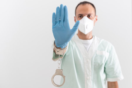 A doctor in a protective medical suit with handcuffs in his hands.の写真素材