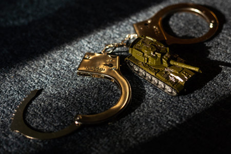 toy tank and handcuffs on a dark background