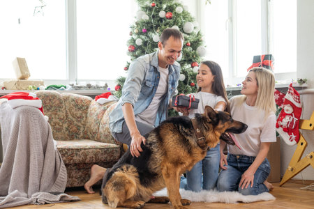 Merry Christmas and Happy New Year. Happy family with dog are waiting for the New Yearwhile sitting near beautiful Christmas tree at home.の写真素材