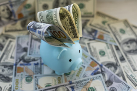 Piggy bank placed up to its nose in a pile of dollars.