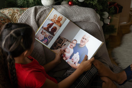 A Little Caucasian girl holding a photobook with her photographs in her hands