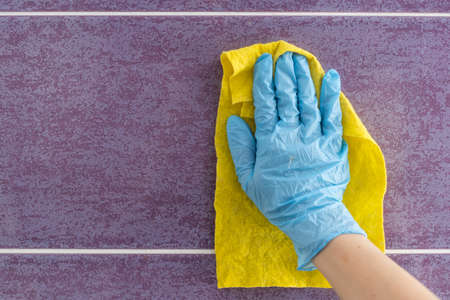 Employee hand in rubber protective glove with micro fiber cloth wiping wall from dust. Maid or housewife cares about house. Spring general or regular clean up. Commercial cleaning company conceptの写真素材