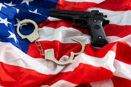 Gun, holster, and handcuffs in front of the American flag, horizontal.の写真素材