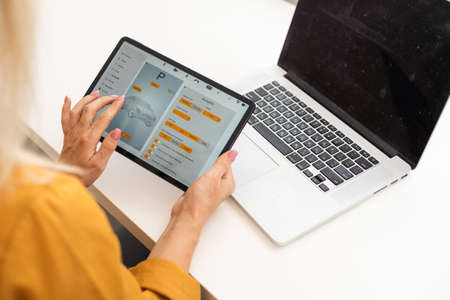 Lets check my timetable. Cheerful young beautiful woman using her touchpad with smile while sitting at her working placeの写真素材