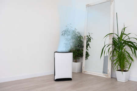 Air purifier in cozy white living room for filter and cleaning removing dust PM2.5 HEPA and virus in home, for fresh air and healthy Wellness life, Air Pollution Conceptの写真素材