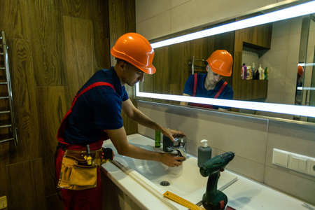 a repairman installs a faucet in a bathroom.の写真素材