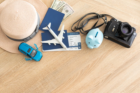passport, tickets, toy plane, camera, piggy bank on wooden floor.の写真素材